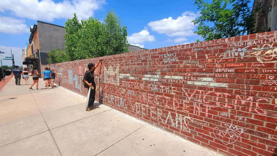 Man with skateboard writing on the wall.
